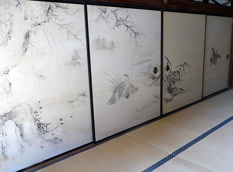 Im Daikakujitempel sind beide Stilrichtungen der Kanomalerei zu finden, einerseits die an den  Suiboku-Stil angelehnte Tuschemalerei und andererseits die an den Yamato-e-Stil angelehnte Farbmalerei. Die hier zu sehende schwarz-weiße Tuschemalerei kommt mit wenigen Pinselstrichen aus. Das Bildmotiv zieht sich über 4 Schiebetüren: Ein Raubvogel schlägt einen Fasan, während ein zweiter entkommen kann (4. Paneele). Die Landschaft ist mit nur wenigen Strichen umrissen. 